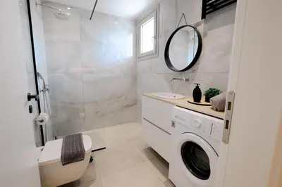 a bathroom with a washing machine and a sink at Olympian Apartments in Ialyssos