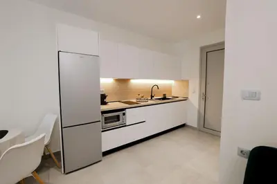 a kitchen with white cabinets and a sink at Olympian Apartments in Ialyssos