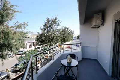 a table on a balcony with a view of a street at Olympian Apartments in Ialyssos