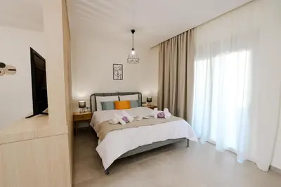 a bedroom with a bed with pink pillows and a television at Olympian Apartments in Ialyssos