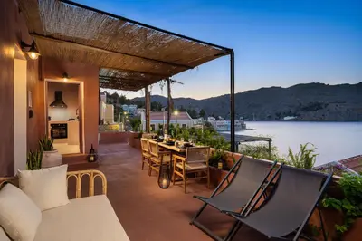 a patio with a table and chairs and a view of the water at Gama luxury living in Symi