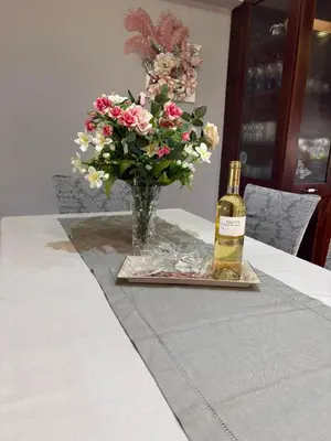 a bottle of wine and a vase of flowers on a table at Casa Maria Tsampika-Spacious Home with 2 Bathrooms & Free Parking in Psinthos