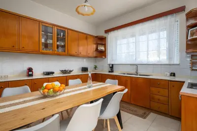 a kitchen with wooden cabinets and a bowl of fruit on a table at Flora Beach House in Kremasti