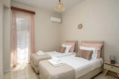 two beds in a room with a window at Flora Beach House in Kremasti