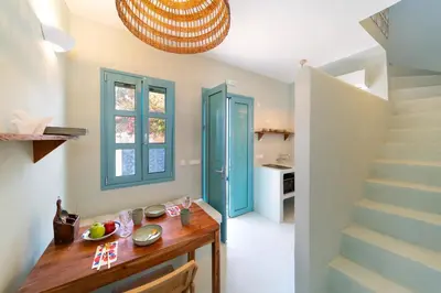 a kitchen with a wooden table and a staircase at Via Vasileia in Kattavía