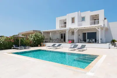 a villa with a swimming pool in front of a house at Hill & Sea View White Pearl Villa in Afantou