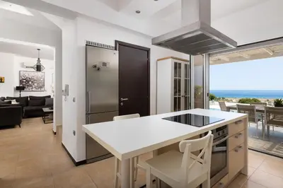a kitchen and living room with a view of the ocean at Hill & Sea View White Pearl Villa in Afantou