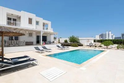 a swimming pool with lounge chairs and a house at Hill & Sea View White Pearl Villa in Afantou