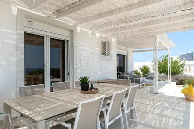 a patio with a wooden table and chairs on a deck at Hill & Sea View White Pearl Villa in Afantou