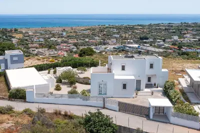 a white house with the ocean in the background at Hill & Sea View White Pearl Villa in Afantou
