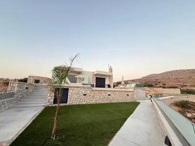 a house with a green lawn in front of it at Blue Infinito Boutique Villa, Infinity Pool , Heated Jacuzzi & Panoramic Sea View in Archangelos