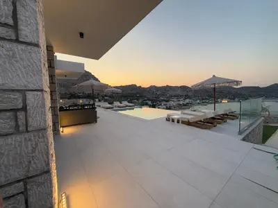 a building with a patio with tables and umbrellas at Blue Infinito Boutique Villa, Infinity Pool , Heated Jacuzzi & Panoramic Sea View in Archangelos
