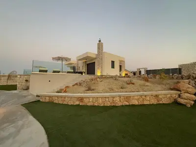 a house with a landscaped yard with a retaining wall at Blue Infinito Boutique Villa, Infinity Pool , Heated Jacuzzi & Panoramic Sea View in Archangelos
