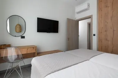 a bedroom with a bed and a mirror and a desk at Blue Infinito Boutique Villa, Infinity Pool , Heated Jacuzzi & Panoramic Sea View in Archangelos