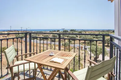 a wooden table and chairs on a balcony with the ocean at Villa Clara in Gennadi