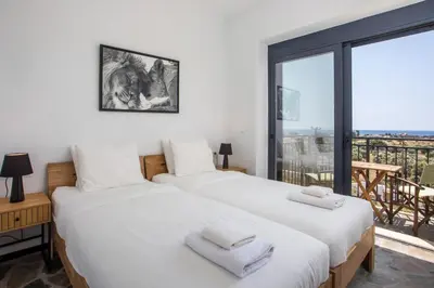 two beds in a room with a large window at Villa Clara in Gennadi