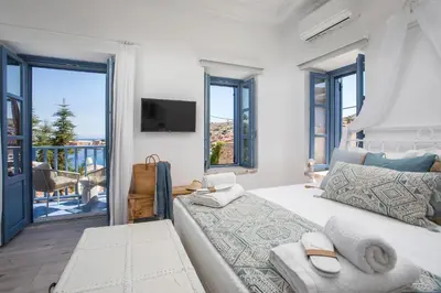 a white bedroom with a bed and a balcony at Anteli Luxury Villa in Halki