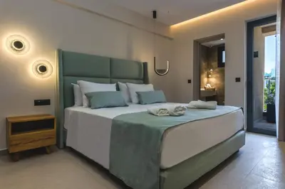 a bedroom with a large bed with a green headboard at Aigialí Essence in Vrachonisída touArchangélou