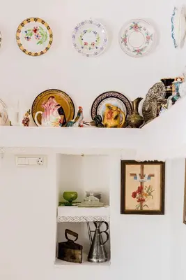 a shelf filled with plates and dishes on a wall at Kamariko Traditional House in Afantou