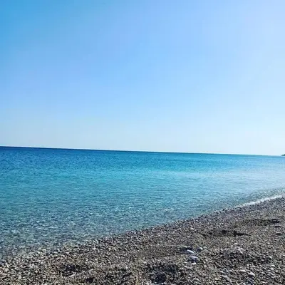 a beach with blue water and a rocky shore at Kamariko Traditional House in Afantou
