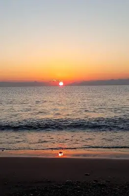 a sunset on a beach with the ocean at Kamariko Traditional House in Afantou