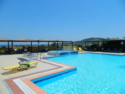 a large swimming pool with chairs and tables in it at Telhinis Hotel & Apartments in Faliraki