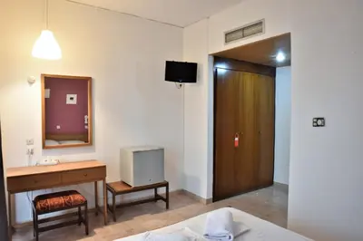 a hotel room with a bed and a desk and a mirror at Telhinis Hotel & Apartments in Faliraki