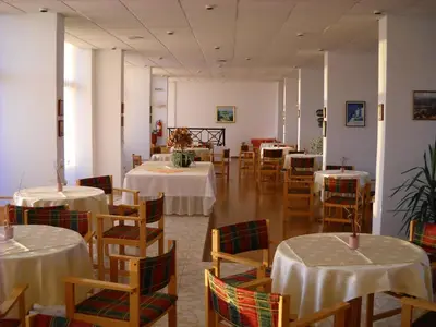 a restaurant with tables and chairs with white tablecloths at Telhinis Hotel & Apartments in Faliraki