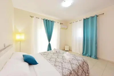 a bedroom with a bed with blue curtains and a window at Seraina House in Pastida