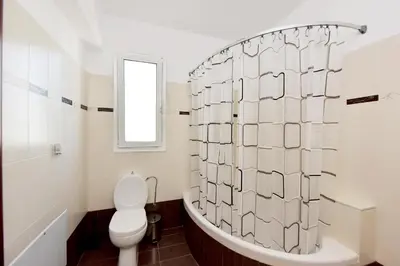 a white bathroom with a toilet and a tub at Seraina House in Pastida