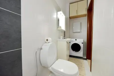 a bathroom with a toilet and a washing machine at Seraina House in Pastida