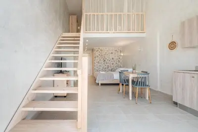 a staircase in a room with a table and a kitchen at Kathara bay Studios in Faliraki