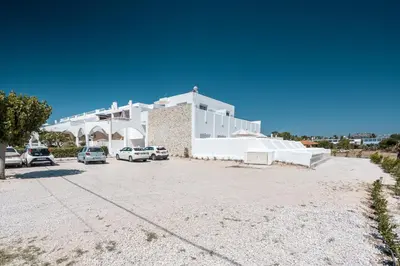 a large white building with cars parked in a parking lot at Kathara bay Studios in Faliraki