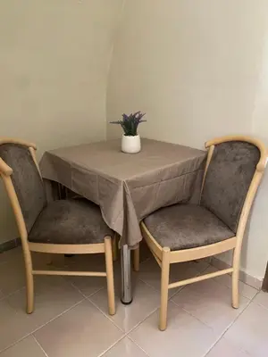 a table with two chairs and a vase of flowers on it at Liora in Rhodes Town