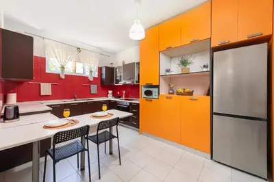 a kitchen with orange cabinets and a white table and chairs at Panormitis House Semi-basement apartment in Pastida