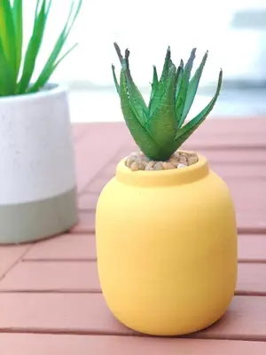 a yellow vase with a plant in it on a table at Panormitis House Semi-basement apartment in Pastida
