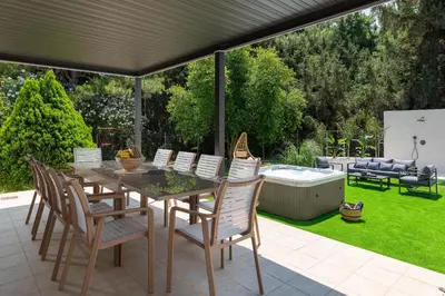 a patio with a table and chairs and a hot tub at Diverso Inn in Koskinou