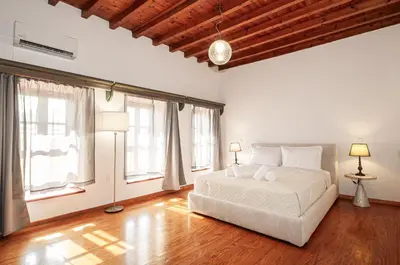 a bedroom with a large white bed and windows at Harmonia - A Sanctuary in the Old Town of Rhodes in Rhodes Town