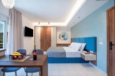a hotel room with a bed and a table and chairs at Dorothea Apartments #1 with sea view in Koskinou