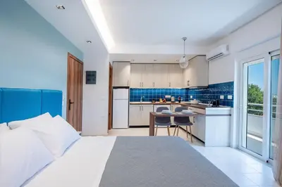 a bedroom with a large bed and a kitchen at Dorothea Apartments #1 with sea view in Koskinou