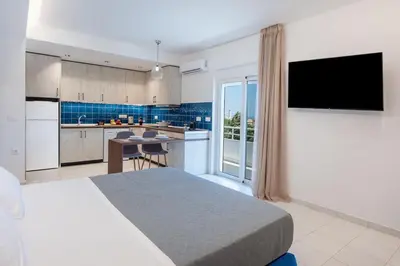 a bedroom with a bed and a kitchen with a television at Dorothea Apartments #1 with sea view in Koskinou