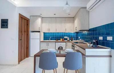 a kitchen with two blue chairs and a table at Dorothea Apartments #1 with sea view in Koskinou