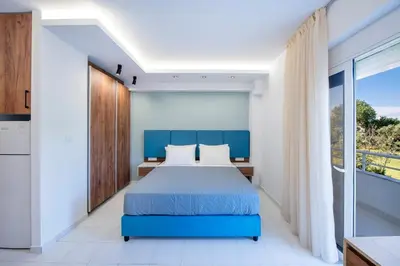 a bedroom with a blue bed and a balcony at Dorothea Apartments #2 with garden view in Koskinou