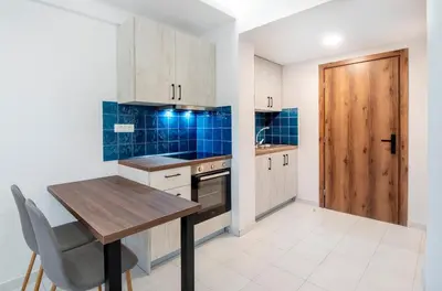 a kitchen with a wooden table and a wooden door at Dorothea Apartments #2 with garden view in Koskinou