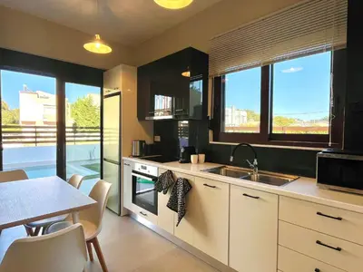 a kitchen with a sink and a table with chairs at Villa Greige in Ialyssos