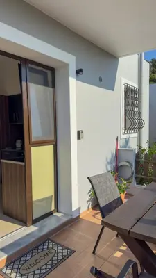 a patio with a wooden table and a wooden door at Angela's Green Escape in Triánta