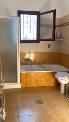 a bathroom with a tub and a toilet and a window at Angela's Green Escape in Triánta