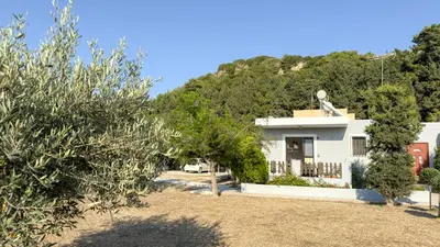 a white house with a hill in the background at Angela's Green Escape in Triánta