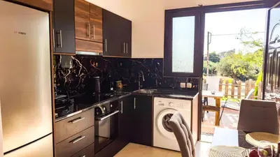 a kitchen with black cabinets and a washer and dryer at Angela's Green Escape in Triánta