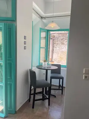 a dining room with a table and chairs and a window at My Symi Apartments in Symi